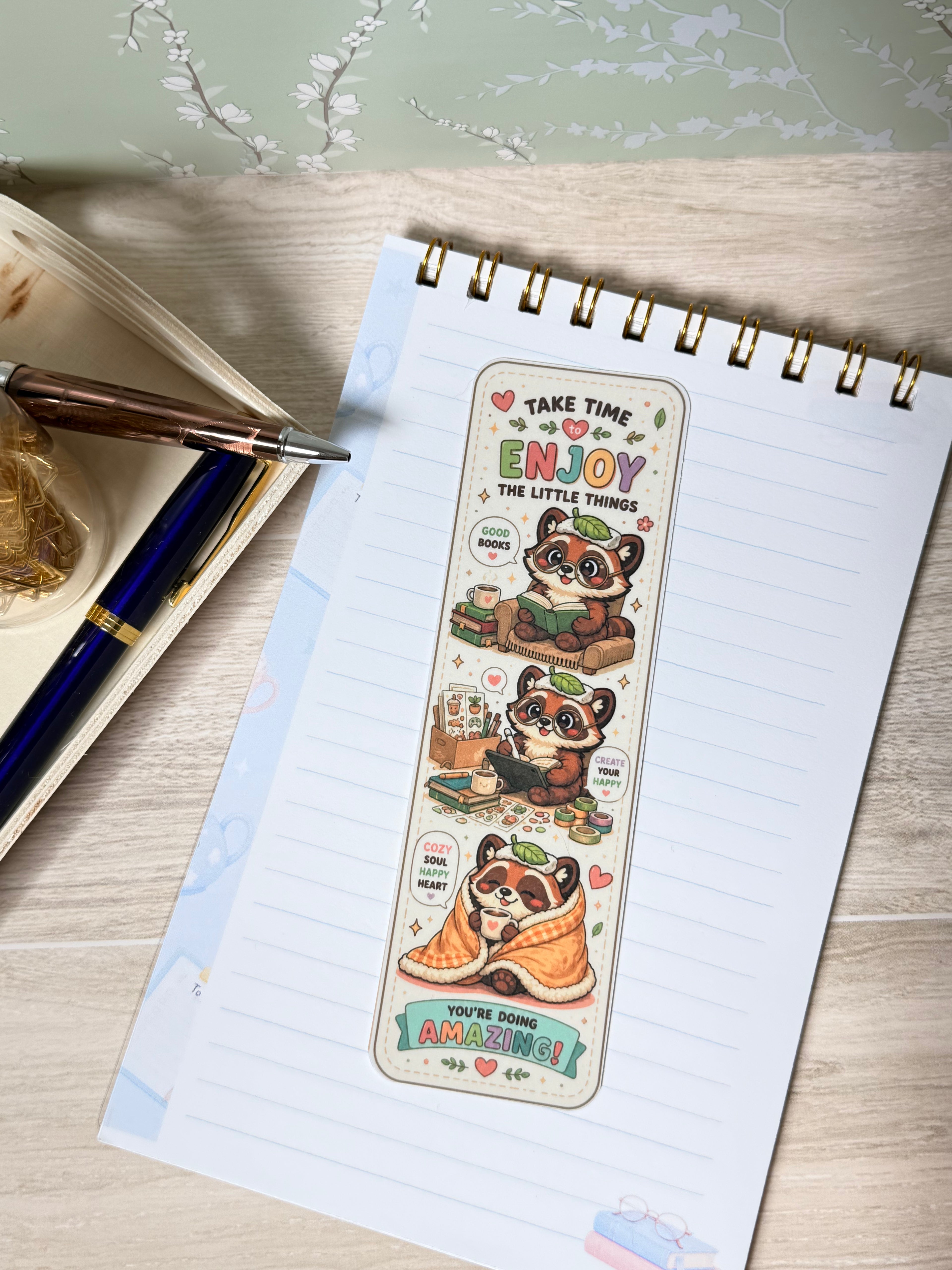 Notebook with a decorative bookmark featuring cartoon characters on a wooden surface.