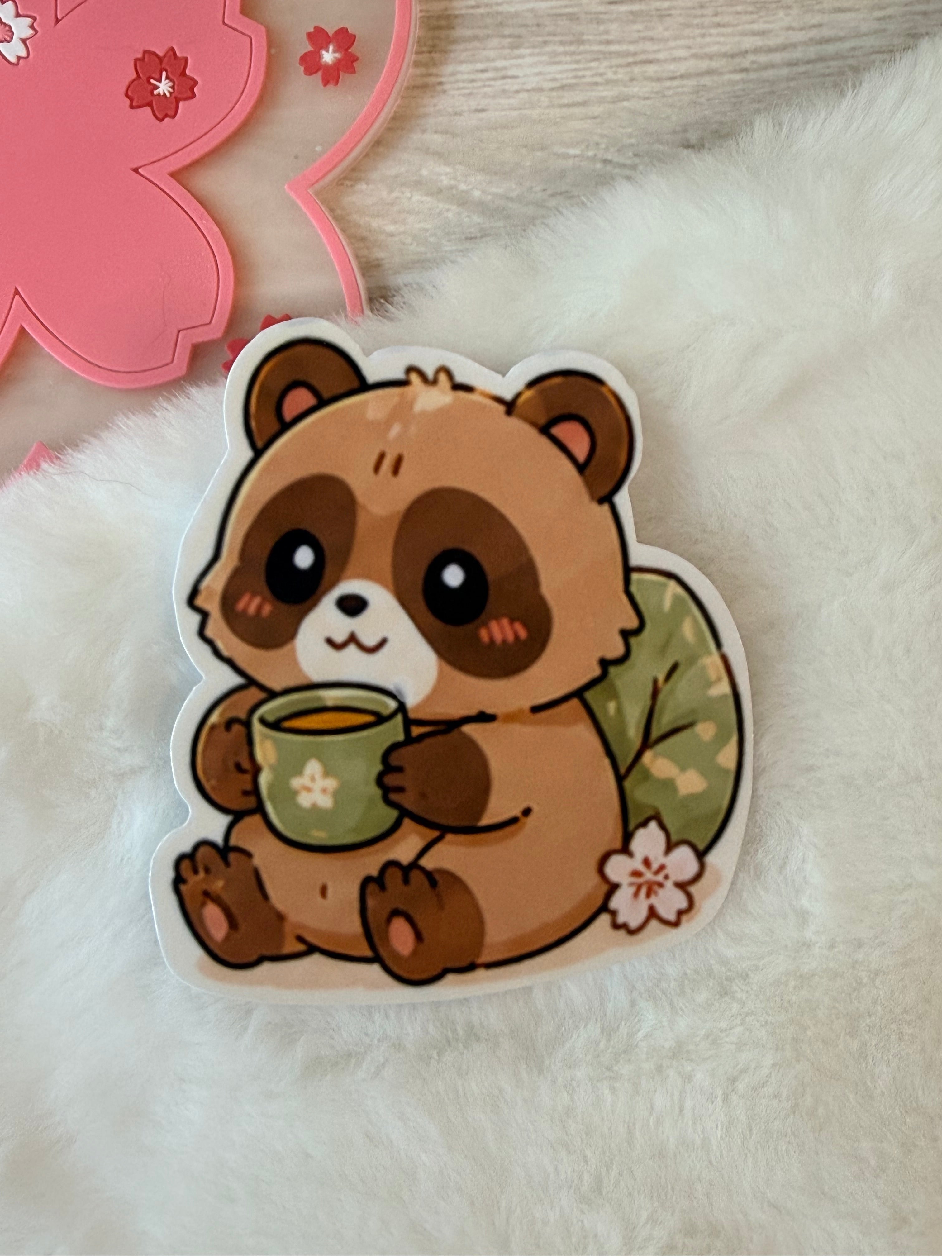 Sticker of a Tanuki holding a mug on a fluffy white surface